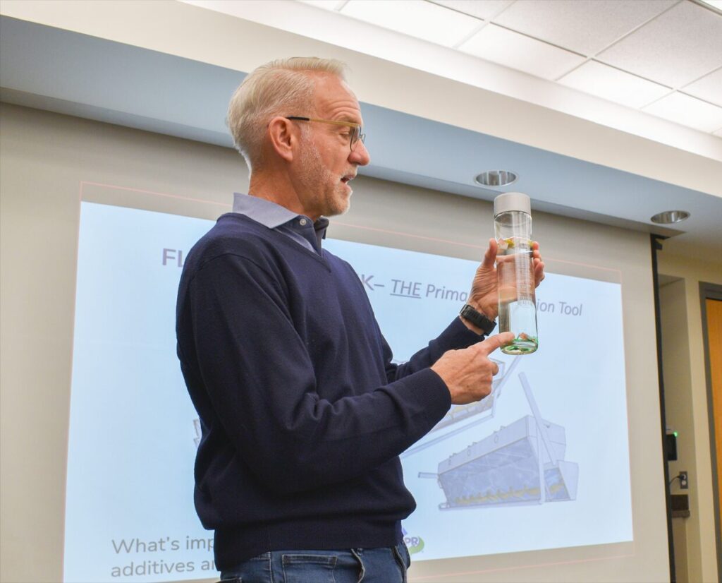 man holding a container filled with liquid at a plastics recycling design training